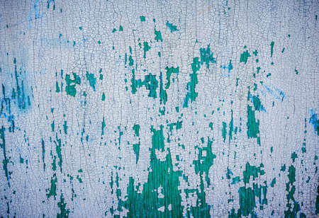 Grunge background - wooden surface with peeling white, green and blue paint. Colorful cracked textureの写真素材