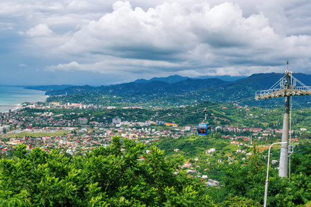 Batumi/Georgia - July 12, 2019: view of cable car station on mountain top. Funicular - blue cabin with passengers, green trees and cloudy sky on background.のeditorial素材