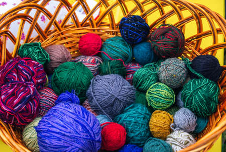 Colorful knitting yarn balls â€“ wool and cotton thread in a wicker basket.