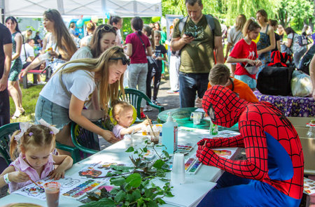 Zaporizhia, Ukraine- June 19, 2021: Charity Family festival:  children, parents and volunteer, dressed like super hero,  participating at art and craft outdoors workshop, making colorful drawingsのeditorial素材