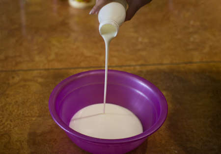 Homemade pancakes cooking process â pouring milk from bottle into the bowlの写真素材