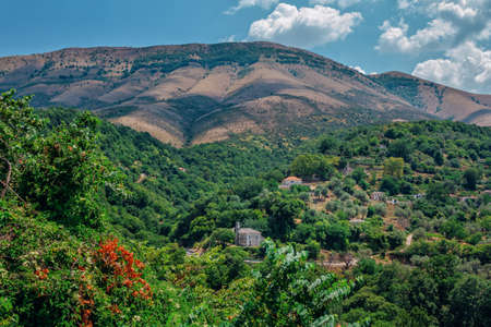 Summer landscape - Albanian mountains, covered with green trees, small village with houses and road and blue sky.の写真素材