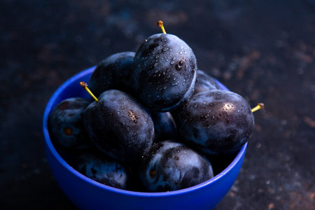 Ripe juicy plums in a bowl on a table. summer fruits.の写真素材