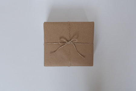 Gift in brown craft paper box on white background, top view, flat lay