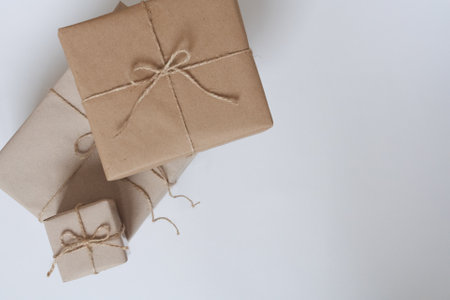 Christmas gifts packed in brown craft paper on a white background. Gifts for the New Year. Birthday gifts. Space for text, top viewの写真素材