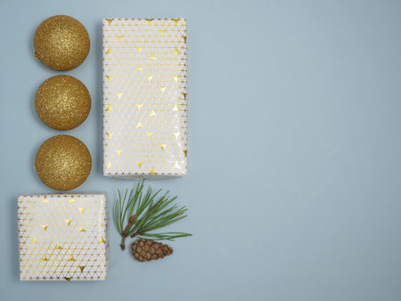 Flat lay christmas background with wrapped gifts and golden sparkling christmas balls on blue...