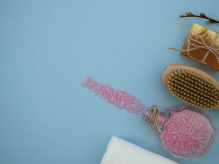 Home spa body treatments, dry wooden body massage, sea salt scrub. Fragrant handmade soap and white towel on a blue background. Home spa body skin care items and tools on blue background with copy space, top viewの写真素材