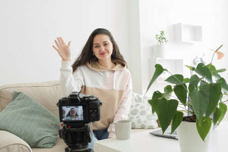 A beautiful young woman blogger or influencer records video on camera for her blog. Online...