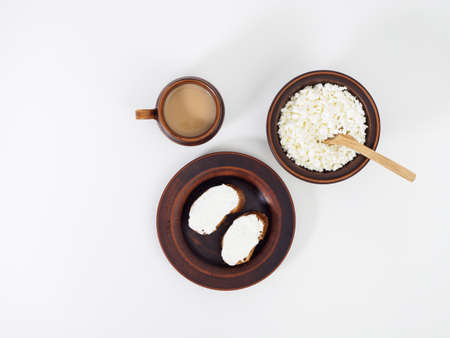 A delicious healthy breakfast with dairy products and aromatic coffee in handmade earthenware. French baguette with curd cheese and a bowl of natural curd. Healthy food. Top view, flat layの写真素材