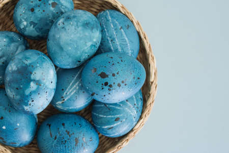 Stylish creative Easter eggs close-up painted like the night sky, space in a basket on a gentle blue background with space for text. Beautiful Easter background. Flat lay, top viewの写真素材