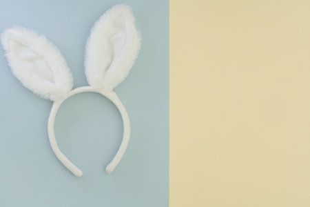 White headband of Easter bunny ears on a two-color pastel background with place for text. Easter minimalistic composition. Top view, flat layの写真素材