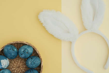 Creative Easter background with Easter eggs in the color of the night blue sky and bunny ears. Two-tone background in two shades of yellow. Space for text, flat lay, top viewの写真素材