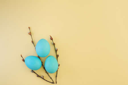 Creative easter bouquet of pussy willow branches and easter blue painted eggs on yellow background with copy space, top view, flat layの写真素材
