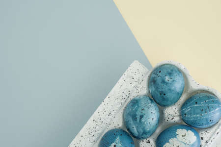 Flat lay easter composition with easter eggs in basket on yellow-blue trending background with copy space, top viewの写真素材