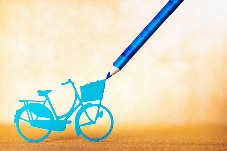 Concept of creation, creativity. Blue paper bicycle on the gold glitter bg, Abstract holidays background. Texture, light bokeh background, Glitter lights background.の写真素材