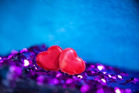 Red hearts on Bright fabric with brilliant paillettes. Rose gold hearts glitter, Abstract holidays background. Texture, light bokeh background, Glitter lights background.の写真素材