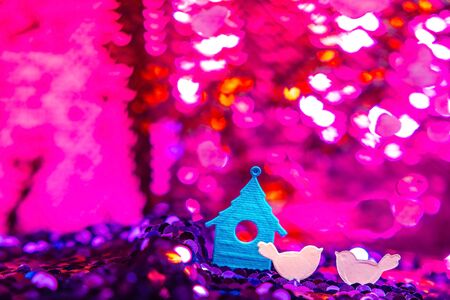 Birds from paper sits on glitter texture, christmas or valentine's day background. Macro shot. Bright fabric with brilliant paillettes. Abstract holidays background. Texture, light bokeh background, Glitter lights background.の写真素材