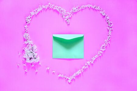 Flowering branch of white  lilac in lime envelope on purple background. Spring blossoming lilac top view, flat layout. Concept spring, summer, Mother's Day holidays, March 8, frame with copy spaceの写真素材