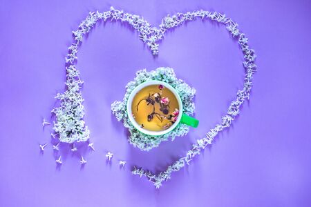 Flowering branch of white  lilac, lime cup of tea on purple background. Spring blossoming lilac top view, flat layout. Concept spring, summer, Mother's Day holidays, March 8, frame with copy spaceの写真素材