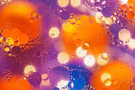 Abstract background. Orange with purple color. Distortions in water with drops of oil. Bright abstraction, ultraviolet. Circles on the waterの写真素材