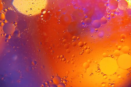 Abstract background. Orange with purple color. Distortions in water with drops of oil. Bright abstraction, ultraviolet. Circles on the waterの写真素材