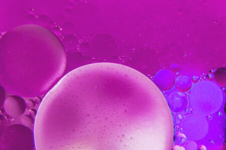 Abstract background with purple and blue bokeh lights color. Distortions in water with drops of oil. Bright abstraction, ultraviolet. Circles on the waterの写真素材