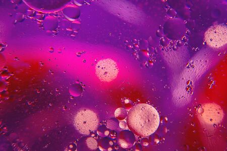 Abstract background with purple and pink bokeh lights color. Distortions in water with drops of oil. Bright abstraction, ultraviolet. Circles on the waterの写真素材