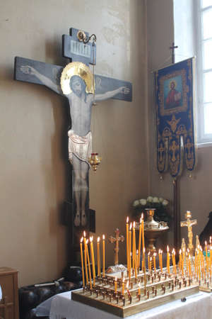 table with burning candle behind the black crucifix with figure of Christ on