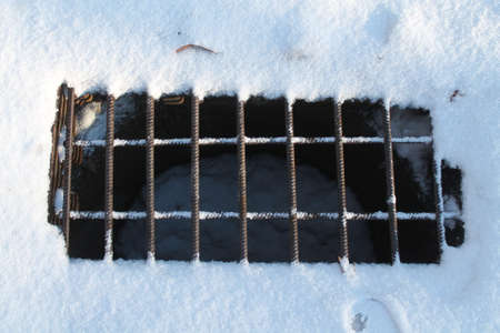 metal solid grille covered entrance in stock of underground communication sink in white snow