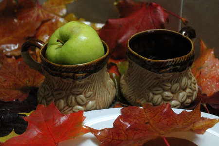 clay beautiful coffee cups with green juicy apple in decorated for autumn morningの写真素材