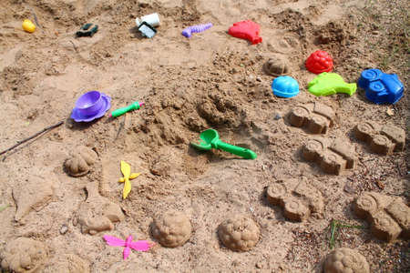 plastic toys lay in the sandbox rest on the sea shore in warm sunny summer day