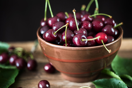Berries of ripe cherries in a glass bowl on a white table.