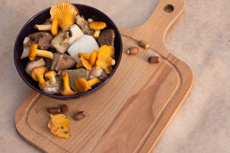 Raw Food. Bowl With Raw Cut Edible Mushrooms (Chanterelle, Cep) And Cutting Wooden Board On Beige Brown Background Top View.の写真素材
