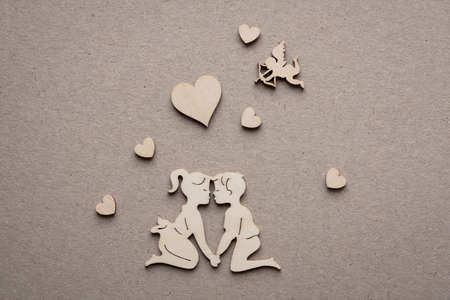 Wooden Figures of Men And Women Are Inclined To Each Other For Kiss On Paper Background. Wooden Silhouettes Of Men And Women, Hearts, Amur.の写真素材