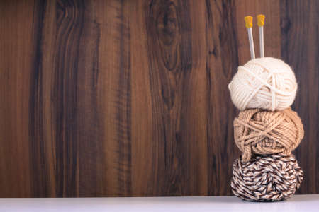Three Threads For Knitting White And Brown Colors And Spokes On Wooden Brown Background With...