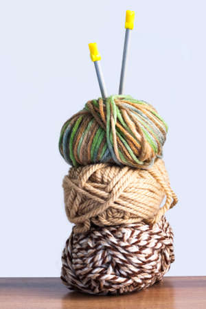 Close Up Of Three Threads For Knitting Green, Brown Colors And Spokes On Wooden Board On White Background.の写真素材
