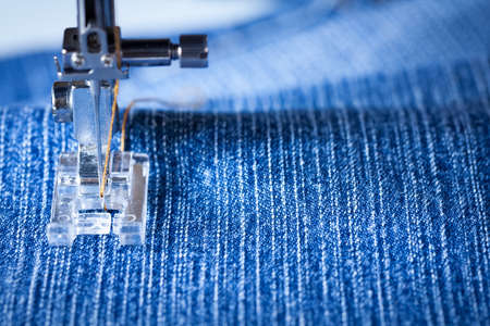Foot Of Sewing Machine With Needle And Yellow Thread Sewing Fabric Of Denim Close Up.の写真素材