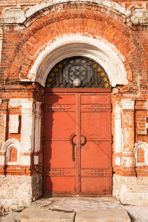 Aged Old Red Metal Door On Old Brick Red Facade. Ancient Style.の写真素材