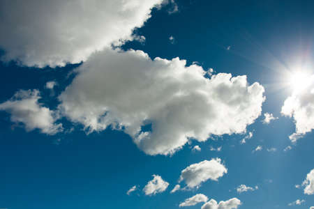 Beautiful Dramatic Fluffy White Clouds On Blue Sky With Bright Sun Close Up.