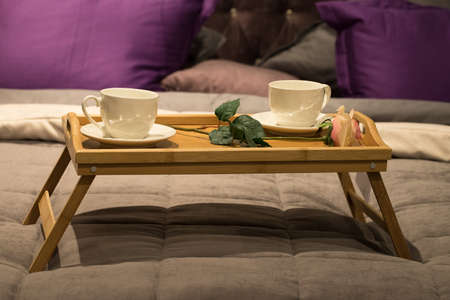 White Ceramic Cups With Rose Flower On Wooden Tray For Breakfast On Bed Close Up.