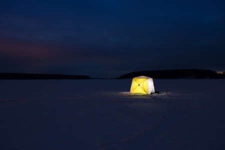 Night fishing. Yellow Fishing Shelter Of Tent On Ice At Night Winter.の写真素材