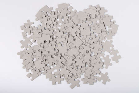 Heap Of Jigsaw Puzzles Grey Color On White Paper Background Top View. Assembly Of Puzzles. Developing Game.の写真素材