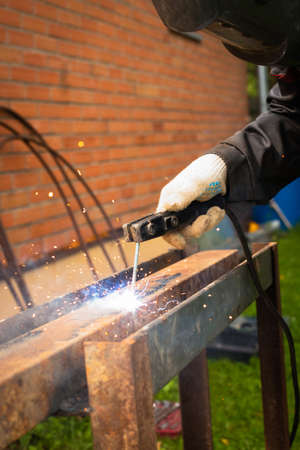 Male Welder In Welding Mask Weld Metal With Welding Machine Outdoor Close Up.の写真素材