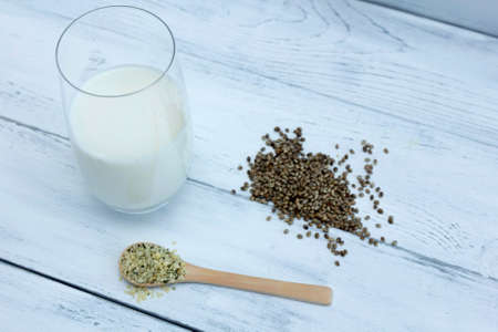 glass with milk from hemp, cannabis and rowos wooden spoon with seeds and seeds out of focus.の写真素材