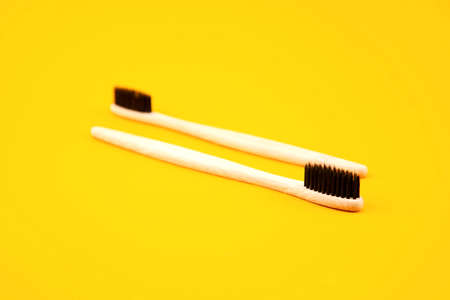 Two toothbrushes made of natural materials lie on a yellow background. Place for text. Refusal of plastic. Zero waste. Oral careの写真素材