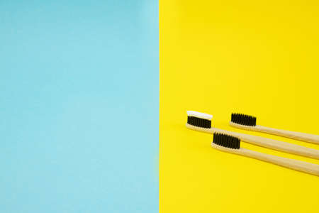 Bamboo eco brushes with natural bristles lie on a blue and yellow background. Save the space. Recycling. No waste. Teeth care. Oral care.の写真素材
