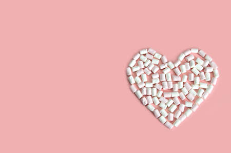 heart laid out of white and pink mini marshmallows on a pink backgroundの写真素材