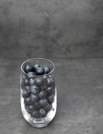 Fresh blueberries in a glass bowl. Delicious blueberries in a glass cup on a gray background. space for textの写真素材