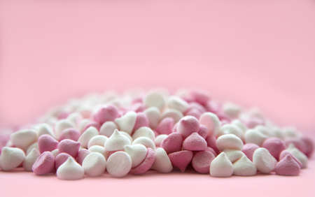 pink and white mini meringues in the shape of drops, which lie on a pink background. Place for text