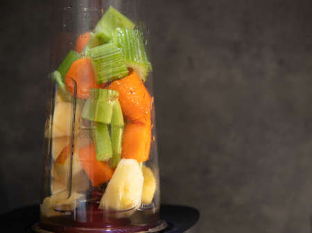 Blender with fresh vegetables. Sliced celery, apple and carrot in a blender cup for a smoothie. Healthy food. Copy spaceの写真素材